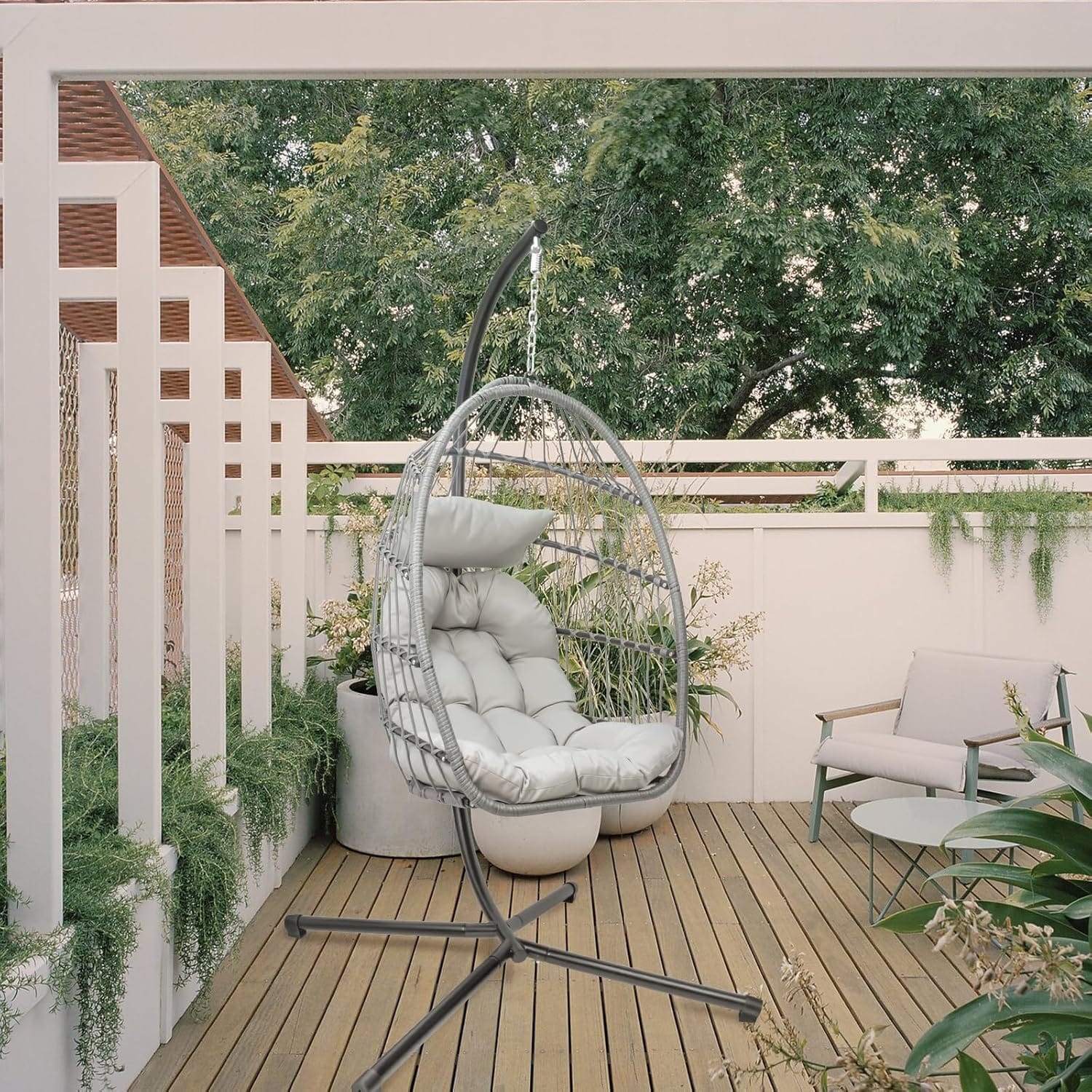 Outdoor hanging egg chair with stand on a garden patio